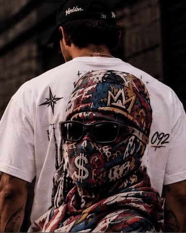 Espalda de camiseta blanca con la gráfica de un encapuchado en rojo, azul y ocre, con una corona y un signo de pesos, y el 092 en el costado