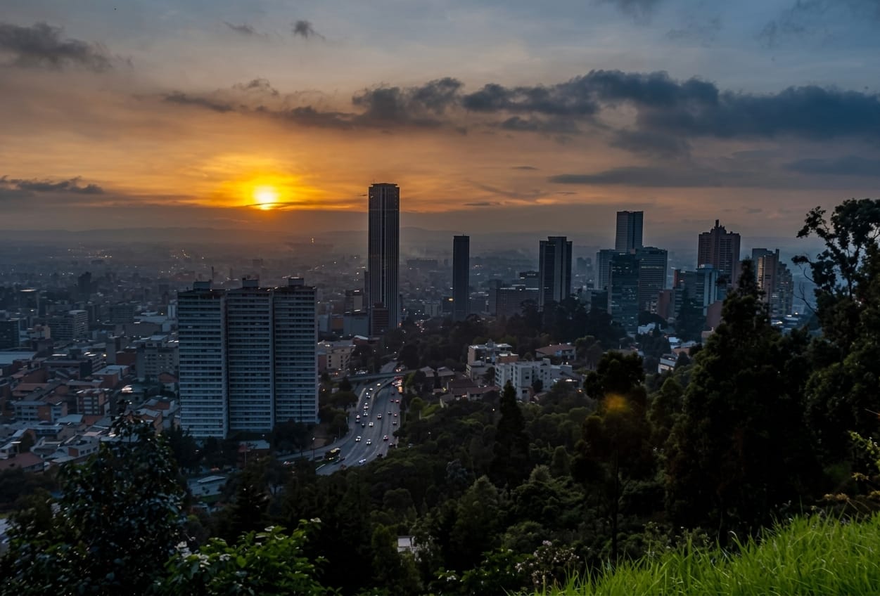Atardecer sobre Bogotá visto desde los cerros: el sol entre las nubes y las torres de la ciudad